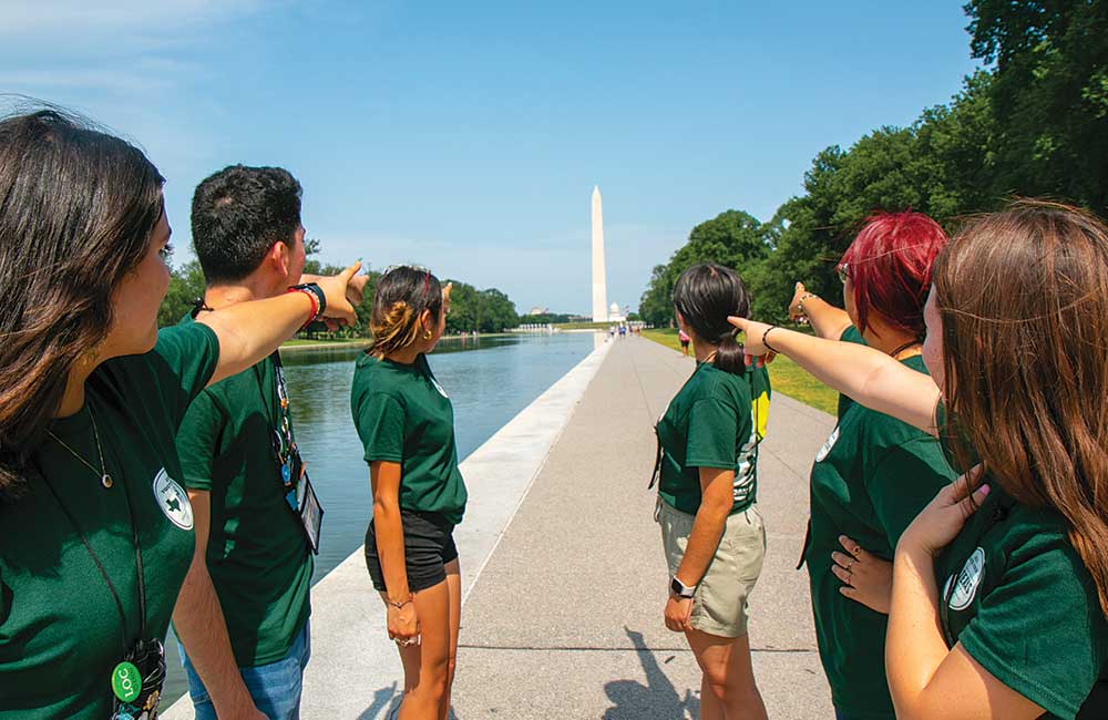 A group of Texas high school students on the National Mall point at the Washington Monument